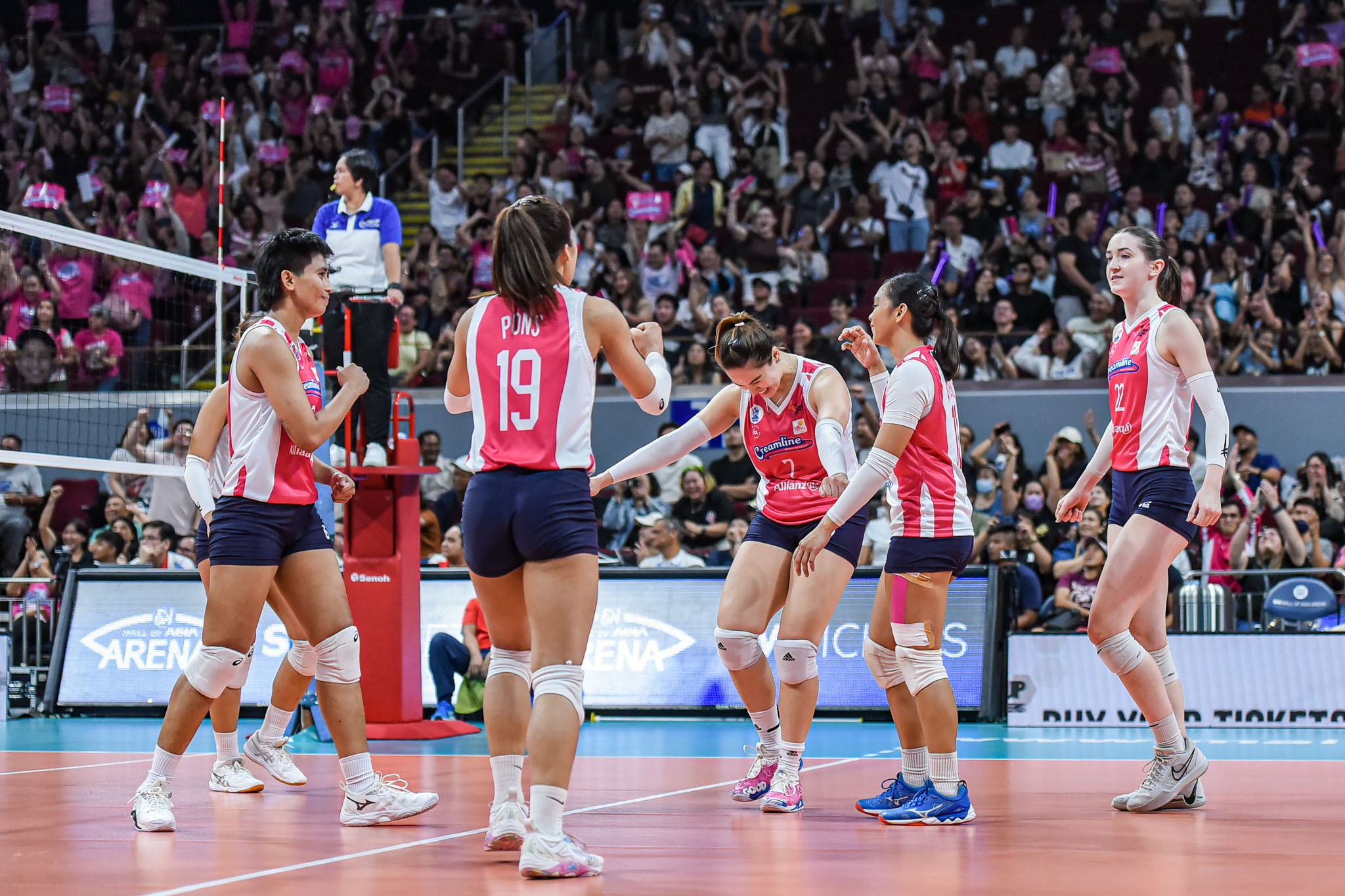 A team photo of Creamline, with their fans at the background.